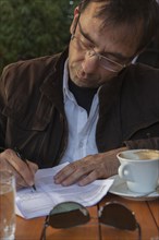Mixed Race man at cafe writing on paperwork