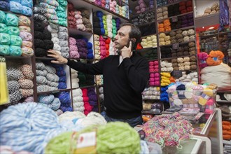 Mixed Race man talking on cell phone at yarn store