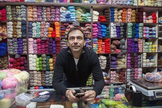 Mixed Race man texting on cell phone at yarn store