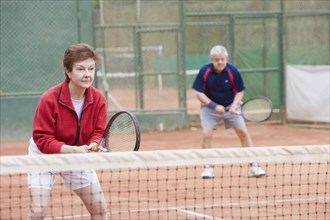 Senior Hispanic couple playing double tennis