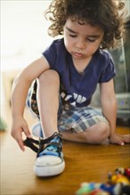 Mixed race boy fastening shoes