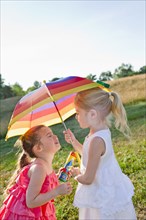 Caucasian girls in field with umbrella