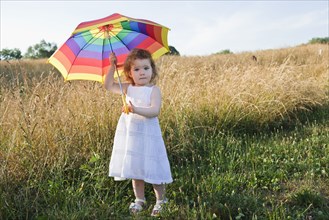 Caucasian girl in field with umbrella