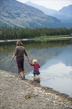 Mother and child walking in still rural lake