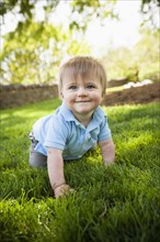 Smiling boy crawling on grass