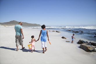 Mixed race family walking on beach