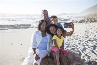 Mixed race multi-generation family taking cell phone selfie on beach