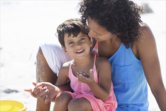 Mixed race mother and daughter playing on beach