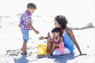 Mixed race mother and children playing on beach