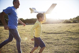 Caucasian father and son flying model airplane in field