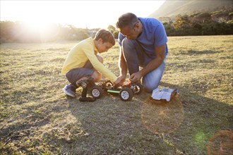 Caucasian father and son playing with remote control cars in field