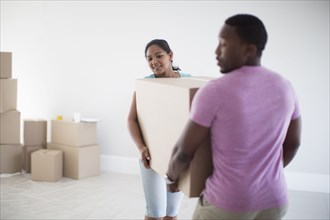 Couple carrying cardboard box in new home