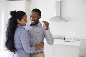 Couple hugging and holding keys in new home