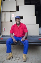 Black delivery man sitting with packages in van