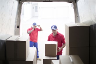 Delivery men unloading packages in van