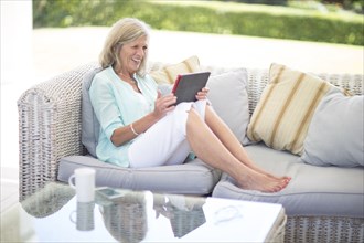 Caucasian woman using digital tablet on sofa outdoors