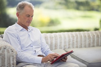 Caucasian man using digital tablet on sofa outdoors
