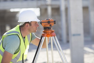 Caucasian surveyor examining construction site
