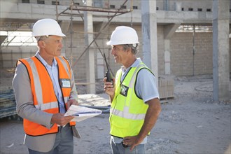 Caucasian architect and construction worker talking at construction site