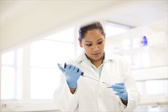 Mixed race scientist pipetting sample into tube in laboratory