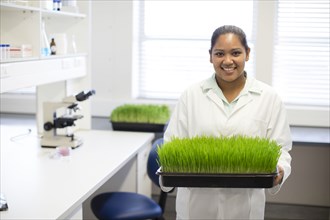 Mixed race scientist holding plants in laboratory