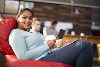 Mixed race businesswoman using cell phone in office lounge