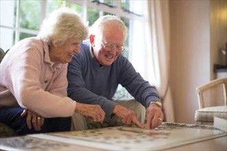 Older couple on sofa solving jigsaw puzzle