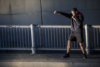 Caucasian man shadow boxing near railing