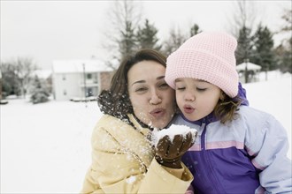 Mother and young daughter playing with snow