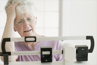 Senior woman weighing self on scale