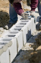 Worker filling cinder blocks with mortar