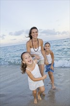 Multi-ethnic mother and daughters playing in surf