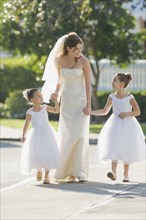 Multi-ethnic bride holding hands with flower girls