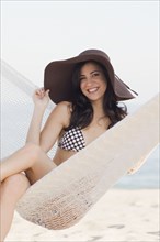 Cuban woman wearing hat in hammock on beach
