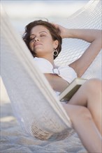 Hispanic woman napping hammock with book