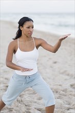African woman practicing yoga at beach