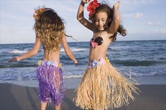 Hispanic girls dancing in hula skirts on beach