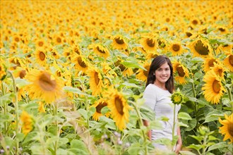 Hispanic woman standing in field of sunflowers