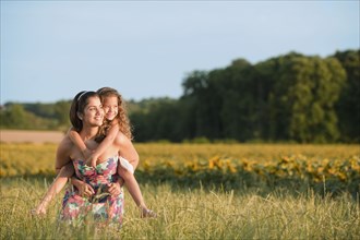 Hispanic mother carrying daughter in rural field
