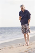 Man using cell phone on beach