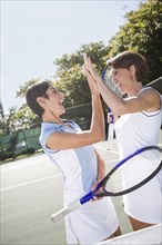 Women high-fiving after a game of doubles tennis