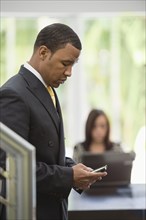 Mixed race businessman text messaging on cell phone