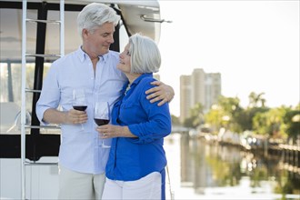 Older Caucasian couple having wine on boat deck