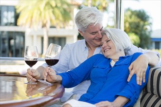 Older Caucasian couple having wine together on boat