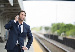 Caucasian businessman talking on cell phone on train platform