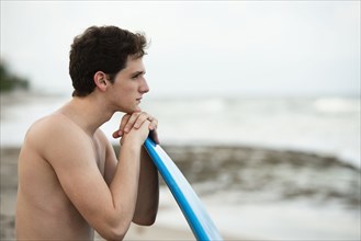 Hispanic man with surfboard on beach