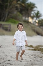 Hispanic boy walking on beach