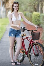 Caucasian woman pushing bicycle on suburban street