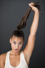 Mixed race woman pulling her ponytail