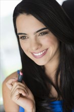 Hispanic woman applying lipstick